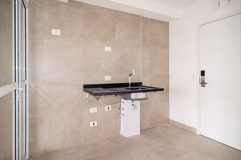 Cozinha com bancada de granito escuro, cuba e parede em porcelanato