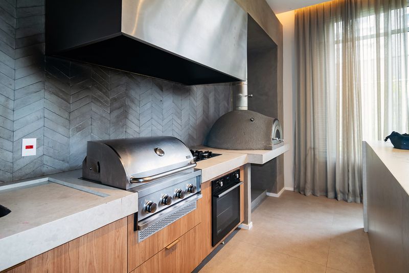 Espaço gourmet com churrasqueira de inox e forno de pizza