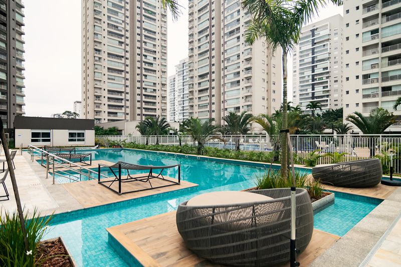 Piscina externa com deck molhado, espreguiçadeiras e palmeiras